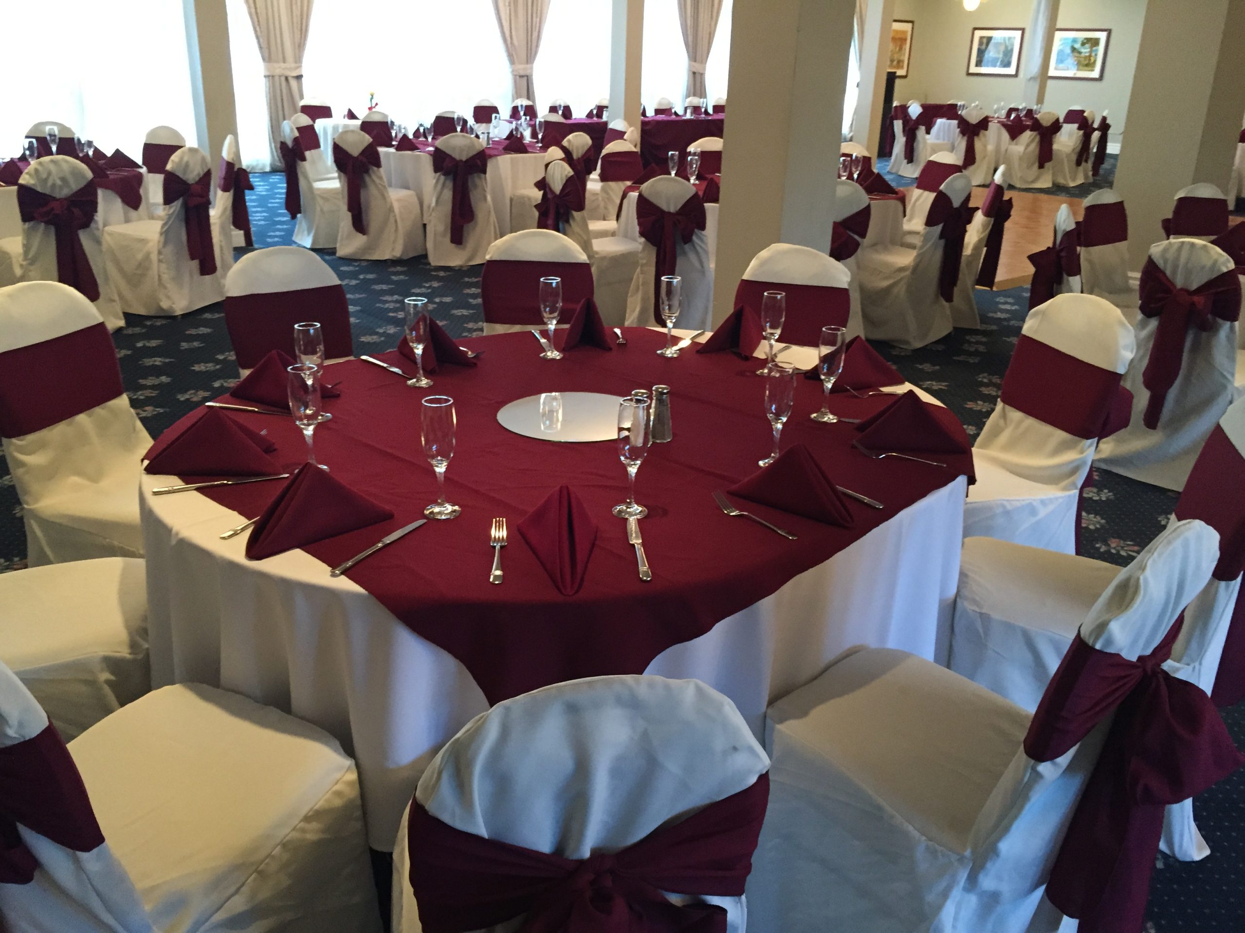 Indoor banquet room set with red table linens and white chair covers