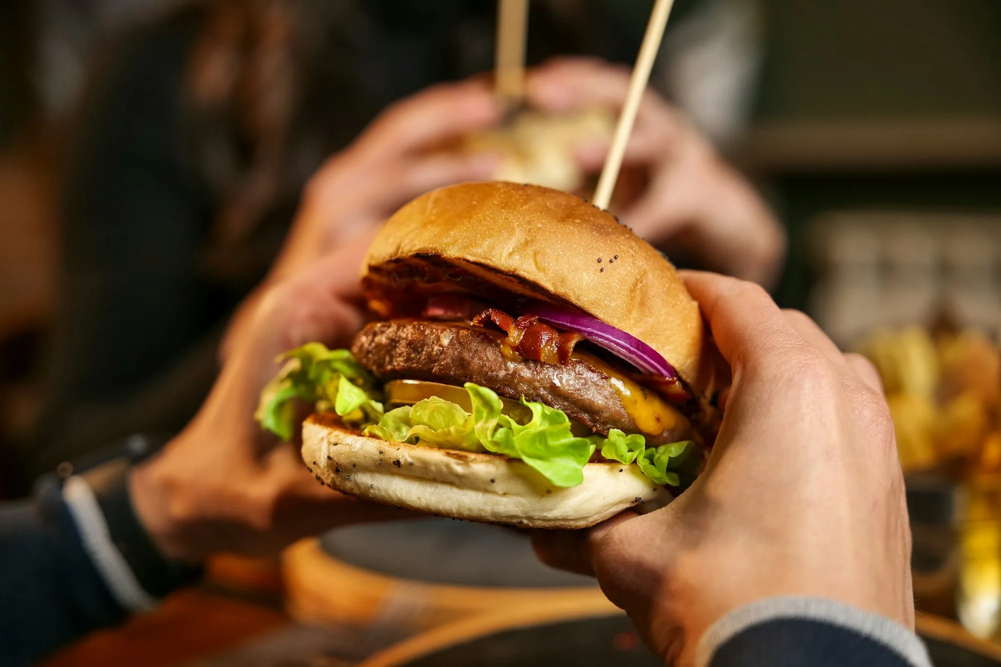 Burger with cheese, bacon, lettuce, and red onion