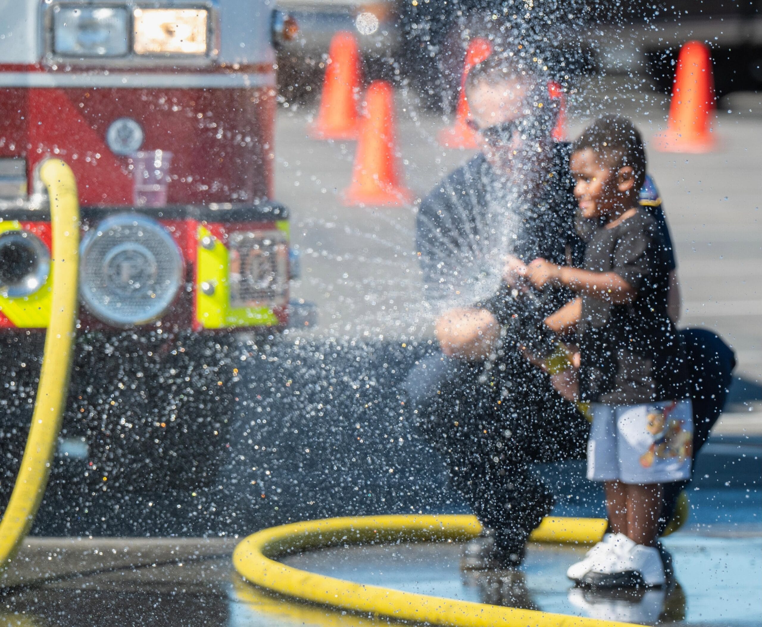 Family enjoying a cool-down with the JFTB Fire Department during Air Show Weekend 2026.